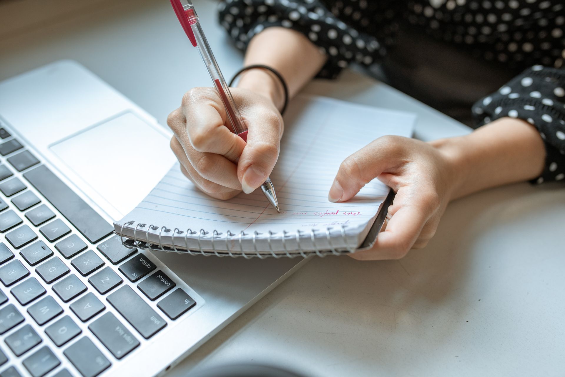 An image showing a contractor checking their payslip on a laptop and making notes.
